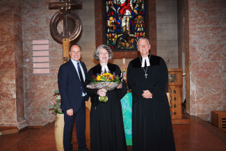 Dekan Peter Bertram (rechts) und Diakonievorstand Andreas Karau bedanken sich bei Gastpredigerin Barbara Hauck mit einem Blumenstrauß.